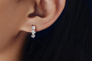 Detailed close-up of 925 sterling silver flower earrings with zircons on an earlobe