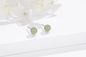 Macro view of minimalist 925 silver stud earrings featuring round green natural stones