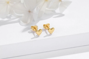 Macro shot of S925 sterling silver stamp on golden heart stud earrings with mirror finish