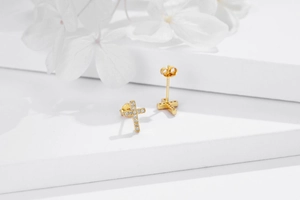 Close-up of gold-plated S925 silver cross stud earrings with cubic zirconia on white stage