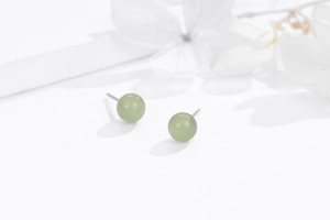 Close-up of minimalist 925 sterling silver stud earrings with round green stone beads
