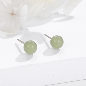 Minimalist 925 sterling silver stud earrings with round green stone on white pedestal
