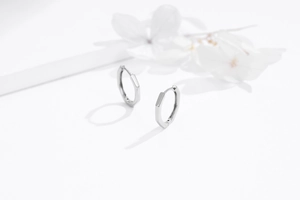 Macro shot of geometric S925 sterling silver hexagonal hoop earrings on white background