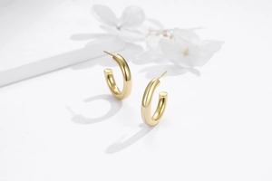 Détail de boucles d'oreilles créoles en C dorées en argent S925 poli et brillant