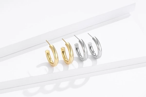 Gros plan sur des boucles d'oreilles créoles S925 minimalistes en or et en argent