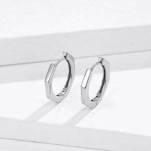 Minimalist S925 sterling silver hexagonal hoop earrings shown on a white geometric stand