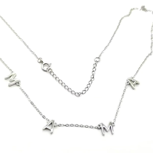 Gros plan du collier avec pendentif lettres MAMA en argent et chaîne réglable sur blanc