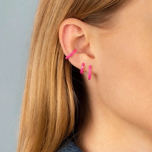 Detail of hot pink enamel hoop earrings and ear cuff on model with single zircon accent