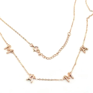 Détail des pendentifs lettres MAMA en or rose sur un collier à chaîne fine pour femme