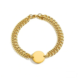 Macro view of golden double-layer chain bracelet with a smooth polished round tag