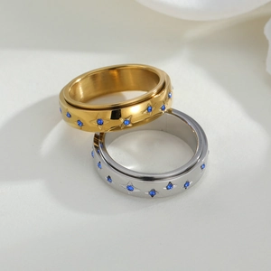 Draaibare spinnerringen in goud en zilver met blauwe zirkoonsterren en gepolijst staal