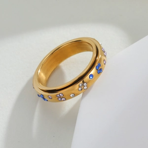 Macro detail of golden spinning ring with colorful flower zircons and rotatable metal band