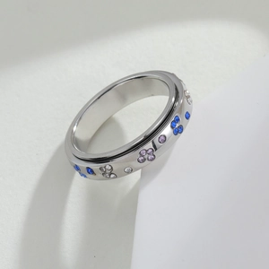 Rotating stainless steel spinner ring with blue butterfly stars on minimalist white background