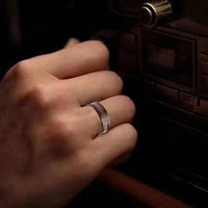 Close-up of men's titanium ring with wood inlay worn on hand with vintage background