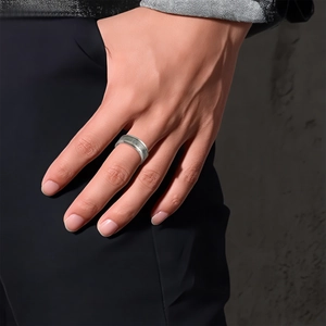 Gros plan d'une bague en acier inoxydable argent mat avec notes de musique gravées