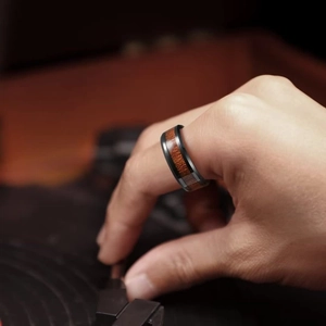 Men's titanium steel ring with wood inlay shown on hand operating a record player