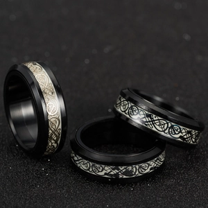 Macro shot of three black stainless steel rotating rings with luminous dragon pattern