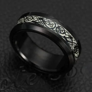 Macro shot of black brushed stainless steel dragon ring with glowing Celtic knot pattern