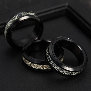 Detail of three black stainless steel spinning rings with Celtic dragon inlay on leather