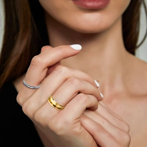 Details von silbernen und goldenen geometrischen Ringen mit Rillen auf der Hand