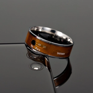 Smart NFC ring with metallic exterior and orange circuit pattern on a smartphone back