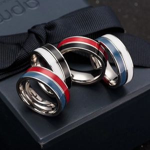 Close-up of four bicolor enamel rotating rings in high-polish stainless steel on a gift box