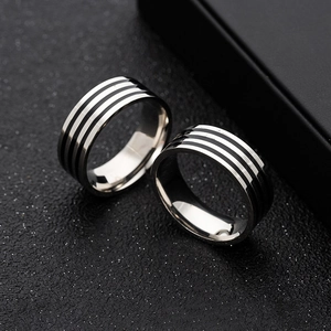 Macro shot of 8mm stainless steel rings with three black enamel stripes on a dark background