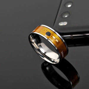 Detailed view of stainless steel NFC ring with circuit board pattern on reflective black surface