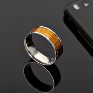 Macro detail of silver NFC smart ring featuring orange circuit board pattern and brand logo