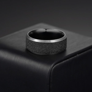 Vue macro d'une bague noire pour homme en acier avec centre sablé et bords brossés