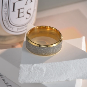 Détail d'une bague large bicolore avec texture givrée argentée et bords polis dorés