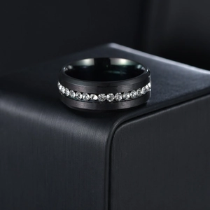 Macro detail of black brushed stainless steel ring with single row clear zircons