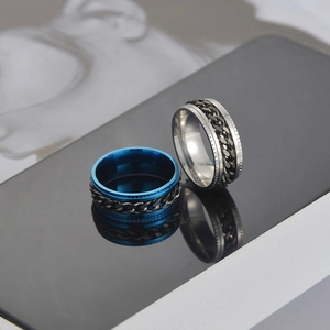 Macro detail of men's stainless steel spinner rings with rotating chains on reflective surface