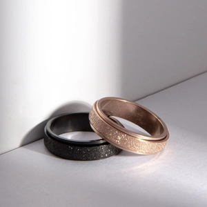 Detail of spinning rings in black and rose gold with glittery frosted finish