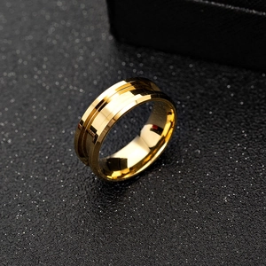 Detail eines breiten goldenen Edelstahlrings mit Mittelrille auf schwarzem Grund