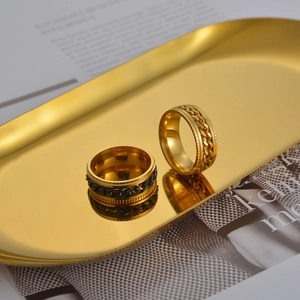Close-up of gold and black chain spinning rings displayed on a golden metal tray