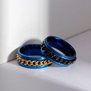 Detail of blue rotatable spinner rings with gold and black cuban chain inlays on steel