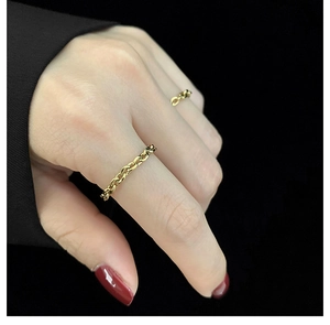 Close-up of minimalist gold link chain rings worn on fingers with a sleek black background