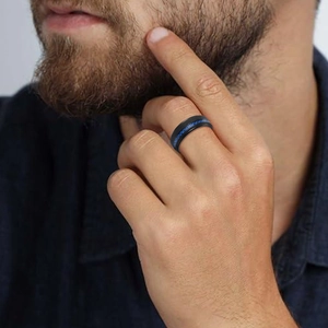 Detailansicht eines mattschwarzen Titanrings mit blauer Carbon-Einlage am Herrenfinger
