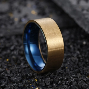 Two-tone brushed gold and blue titanium steel ring for men on black pebble stone background