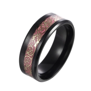 Macro shot of black stainless steel ring featuring pink inlay and golden Celtic dragon pattern