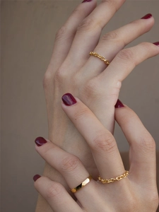 Close-up of three-piece gold chain ring set with geometric facets on a female model's hand