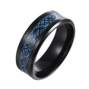 Close-up of black stainless steel ring with blue Celtic dragon pattern on white background