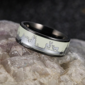 Macro shot of luminous forest and elk engraving on a black titanium steel ring