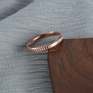 Modern rose gold titanium steel gear ring with vertical stripes on a wooden block