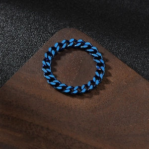 Detailed close-up of a blue cuban chain ring made of polished stainless steel on wood