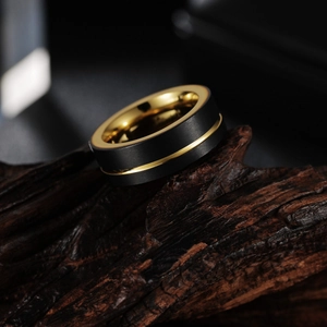 Bague pour homme 8mm en acier noir brossé et doré sur support en bois naturel