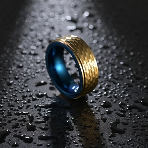 Bague en acier titane bicolore or et bleu martelé pour hommes sur surface de gouttelettes