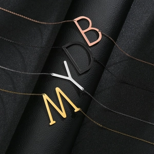 Lot de quatre colliers avec lettres capitales en or, noir, argent et or rose sur support