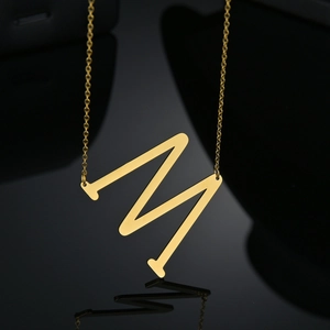 Détail du grand pendentif lettre M doré avec finition miroir sur chaîne fine dorée